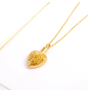 Detail of a golden heart cremation urn pendant with filigree and yellow pavé crystals
