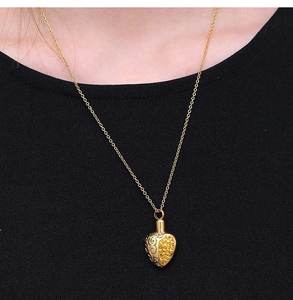 Close-up of golden heart pendant featuring intricate hollow patterns and pave yellow stones