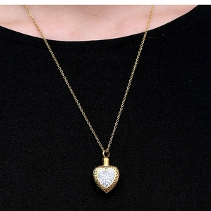 Primo piano di una collana a cuore dorata con cristalli scintillanti su sfondo nero