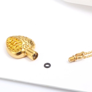 Golden heart-shaped perfume urn necklace with yellow rhinestones and screw closure detail