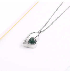 Macro detail of silver heart locket with green crystals and Forever In My Heart engraving