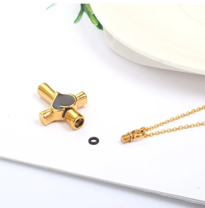 Dettaglio della collana urna cuore croce dorata con tappo a vite e set imbuto