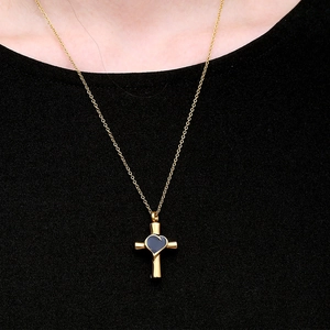 Collana a croce d'oro lucido con pendente a cuore blu indossata su nero