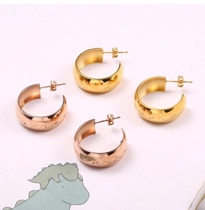 Detailed view of C-shaped earrings with cross star pattern in gold and rose gold finish