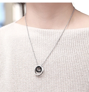 Detail view of double ring pendant necklace in silver and black on a female model neck