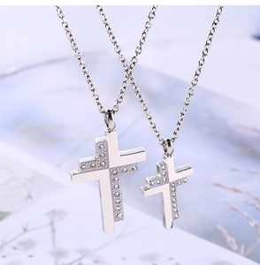 Close-up of titanium steel cross pendants with inlaid diamonds for couples