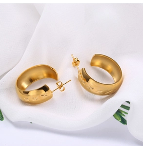 Detail of gold-plated stainless steel C-shaped earrings with cross-engraved texture