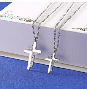Detailed view of silver stainless steel cross necklaces with crystals on blue background