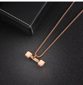 Gros plan détaillé du pendentif haltère en or rose avec chaîne sur boîte à bijoux noire