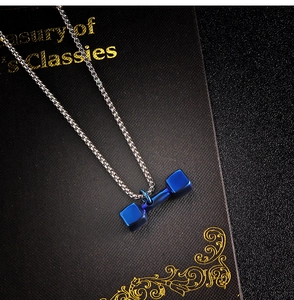 Gros plan du pendentif haltère bleu sur une chaîne en acier inoxydable avec fond de livre