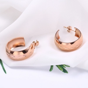 Elegant rose gold C-shaped stainless steel earrings with cross pattern on white silk fabric