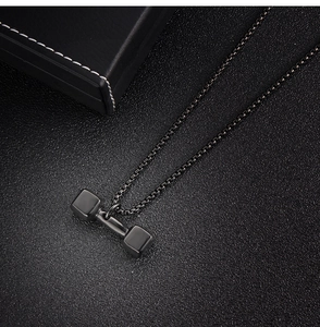 Vue macro du pendentif haltère en acier noir avec une chaîne à perles carrées robuste