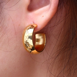 Golden C-shaped cross pattern hoop earrings for women showing elegant texture on ear