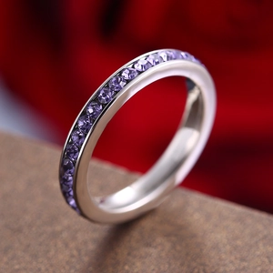 Elegant silver eternity ring with purple round-cut gemstones on a dark background