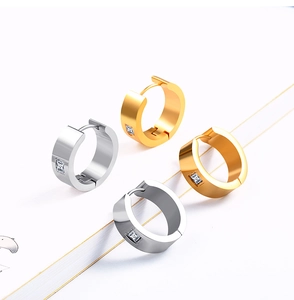 Détail de boucles d'oreilles créoles en acier doré et argenté avec zircon carré