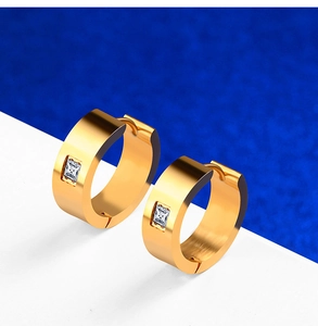 Détail des boucles d'oreilles huggies en acier doré avec un zircon de coupe carrée