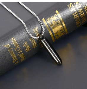Gros plan du pendentif balle noir mat avec chaîne vénitienne en argent sur fond de livre