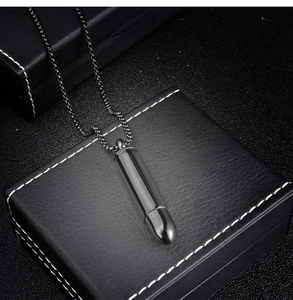 Gros plan d'un pendentif en forme de balle en acier inoxydable noir avec chaîne assortie