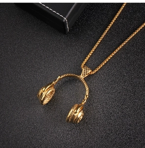 Détail d'un collier pendentif casque hip-hop doré avec oreillettes texturées sur fond noir