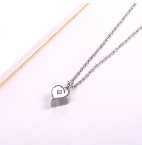 Dettaglio macro del ciondolo a cuore in acciaio argento con zircone cubico scintillante