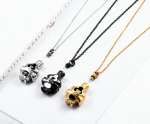 Detalle de tres collares de urna de corazón en acabados plata, negro y dorado