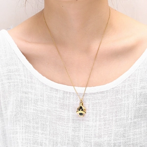 Primer plano de collar urna dorado con colgante negro en modelo para cenizas