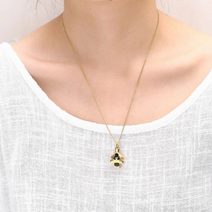 Elegante collar de acero inoxidable dorado con colgante de oso negro en una modelo