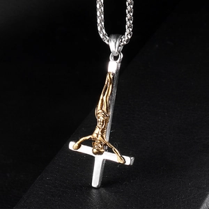 Macro detail of silver inverted cross with golden Jesus figure and steel wheat chain