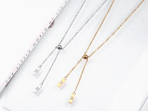 Détail du fermoir coulissant et des pendentifs barres avec zircon sur le collier à gland