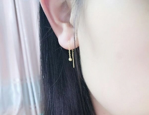 Gros plan d'élégantes boucles d'oreilles traversantes en or 18 carats sur une oreille