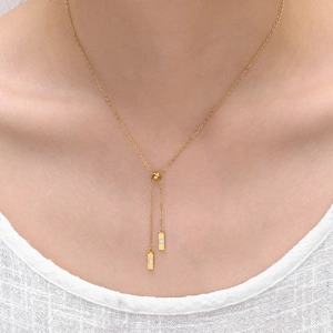Détail d'un long collier en Y doré avec des pendentifs en cristal portés par un mannequin