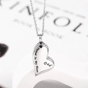 Macro view of heart-shaped stainless steel memorial urn necklace engraved with Dad