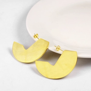 Detail view of gold fan-shaped stud earrings featuring brushed metal texture and geometric arc