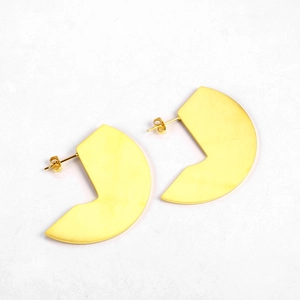 Detailed macro view of gold-plated geometric fan-shaped earrings with a brushed metal finish