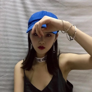 Dettaglio cappellino blu e orecchini a catena d'argento lunghi su modella stile street