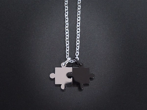 Detailansicht der ineinandergreifenden Puzzle-Anhänger in Silber und Schwarz für Paare