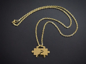 Detail von ineinandergreifenden Gold-Puzzle-Anhängern an O-Ketten mit Polierung