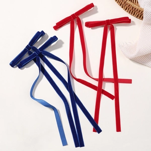 Elegant long velvet bow hair clips in navy blue and red colors on a cream background