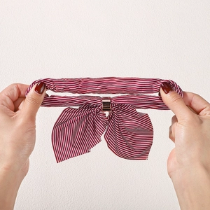 Elastic red and white striped bow hair tie being stretched to show flexibility and material
