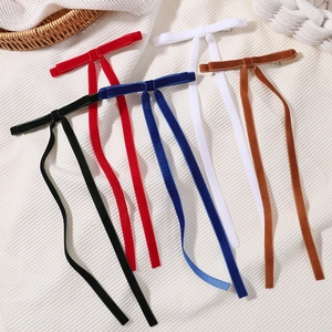 Detail of five velvet bow hair clips with long ribbons in diverse colors on fabric