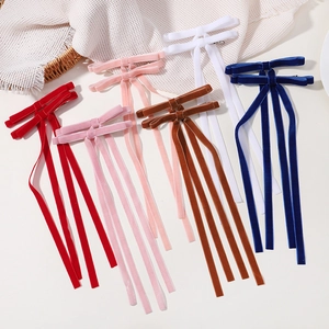 Detailed view of six velvet bow hair clips with long ribbons in assorted colors