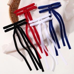 Close-up of velvet bow hair clips in red, blue, white, and black with long ribbon streamers