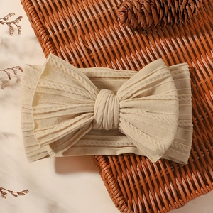 Detail of baby jacquard headband with large bow in soft beige knit rib texture