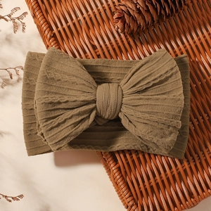 Detailed close-up of brown ribbed knit baby headband featuring a large soft textured bow