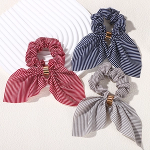 Close-up of retro striped bow hair scrunchies with golden metal buckles in red, navy, and gray
