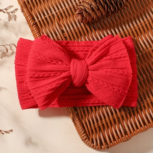 Detail of red jacquard baby headband with large bow on rustic basket background