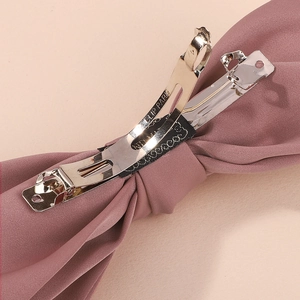 Detail of metal spring clip on dusty pink fabric with engraved CLIP PARIS lettering