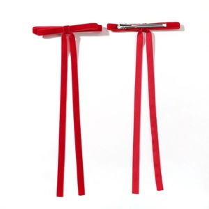 Pair of red velvet bow hair clips with long elegant streamers on a white background