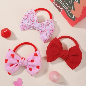 Detailed close-up of three bow hair ties with red hearts and waffle texture fabric