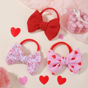 Detailed view of three bow hair ties with red hearts and waffle texture fabric
